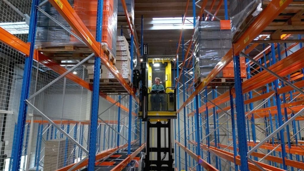 Persoon die een smallegangentruck bestuurd in een magazijn